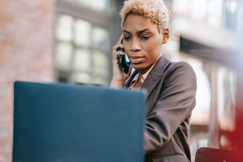 woman-calling-on-smartphone-while-watching-laptop